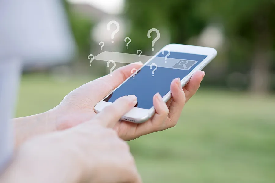 hands holding a smartphone with an empty search bar and many question marks