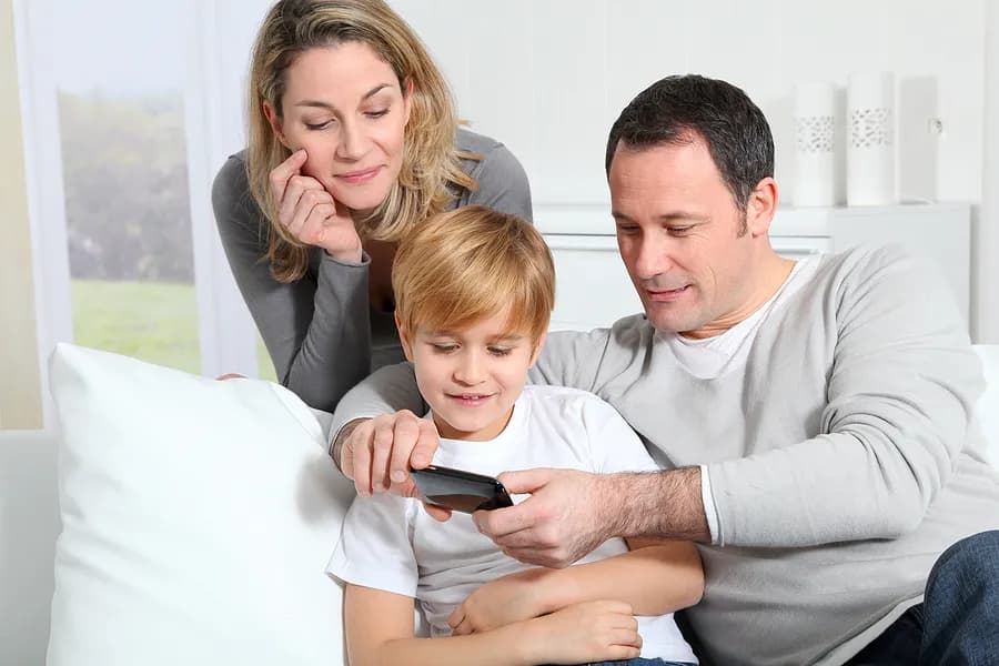 Mother, father, and child looking at mobile phone.