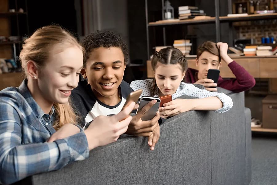 Four teenagers looking at their mobile phones.
