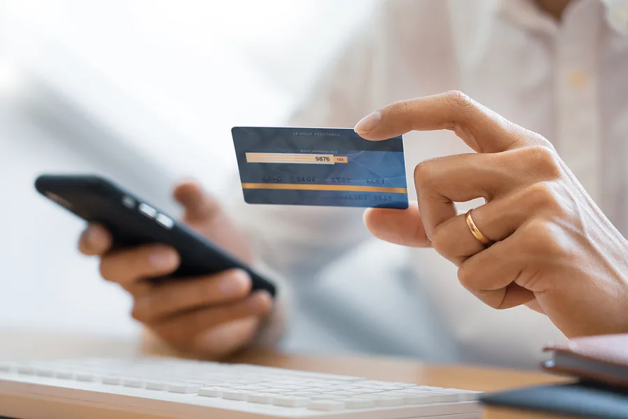 Hands holding a cell phone and a credit card.