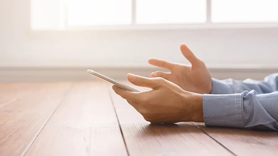 Person holding an iPhone near a window, representing how to unlock iPhone passcode without computer.