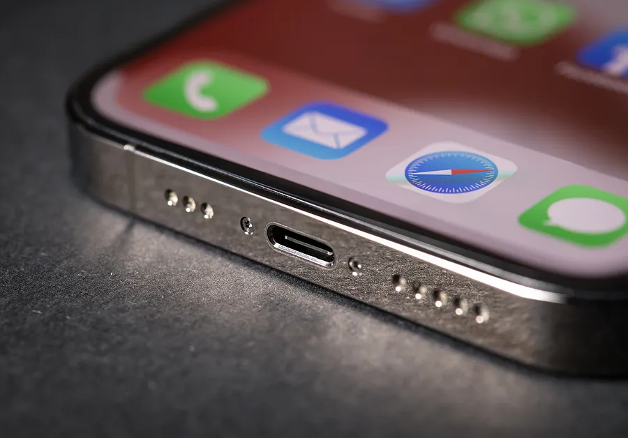 Close-up of an iPhone charging port with app icons visible on the screen, representing iPhone not charging issues.