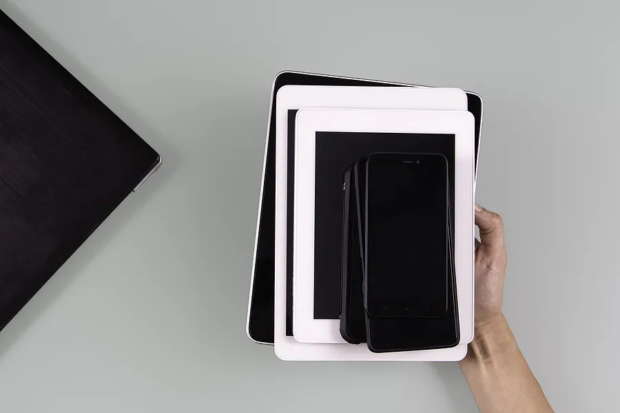 Hand holding stacked mobile devices including smartphones and tablets, symbolizing the growing market and future trends of refurbished phones