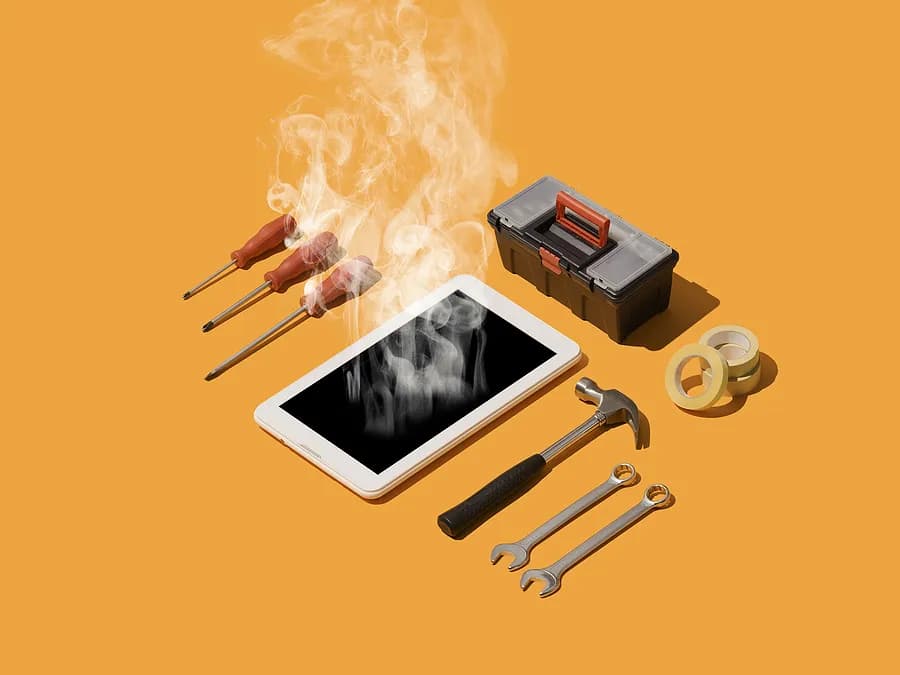 smartphone emitting smoke lies on an orange surface surrounded by repair tools, including screwdrivers, wrenches, a hammer, tape, and a small toolbox, symbolizing phone overheating and repair.